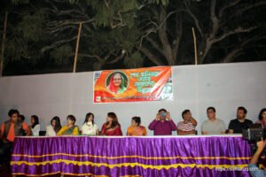 a group of people sitting in সুফি ফারুক এর আমন্ত্রণে পান্টি বাজারের অনুষ্ঠানে যোগ দিয়েছেন তারকারাchairs and a man standing in front of a stage